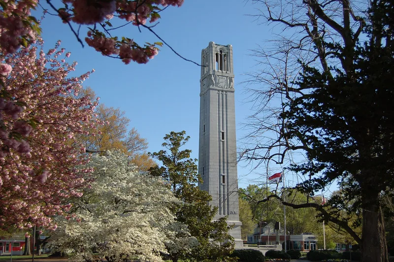 The Memorial Belltower at NC State framed by spring trees